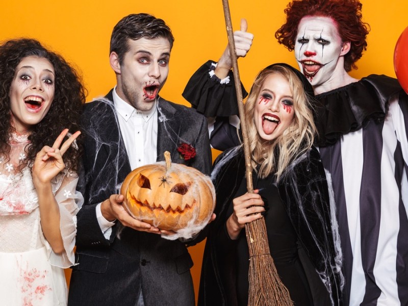 Vier Personen in Halloweenkostümen lachen.