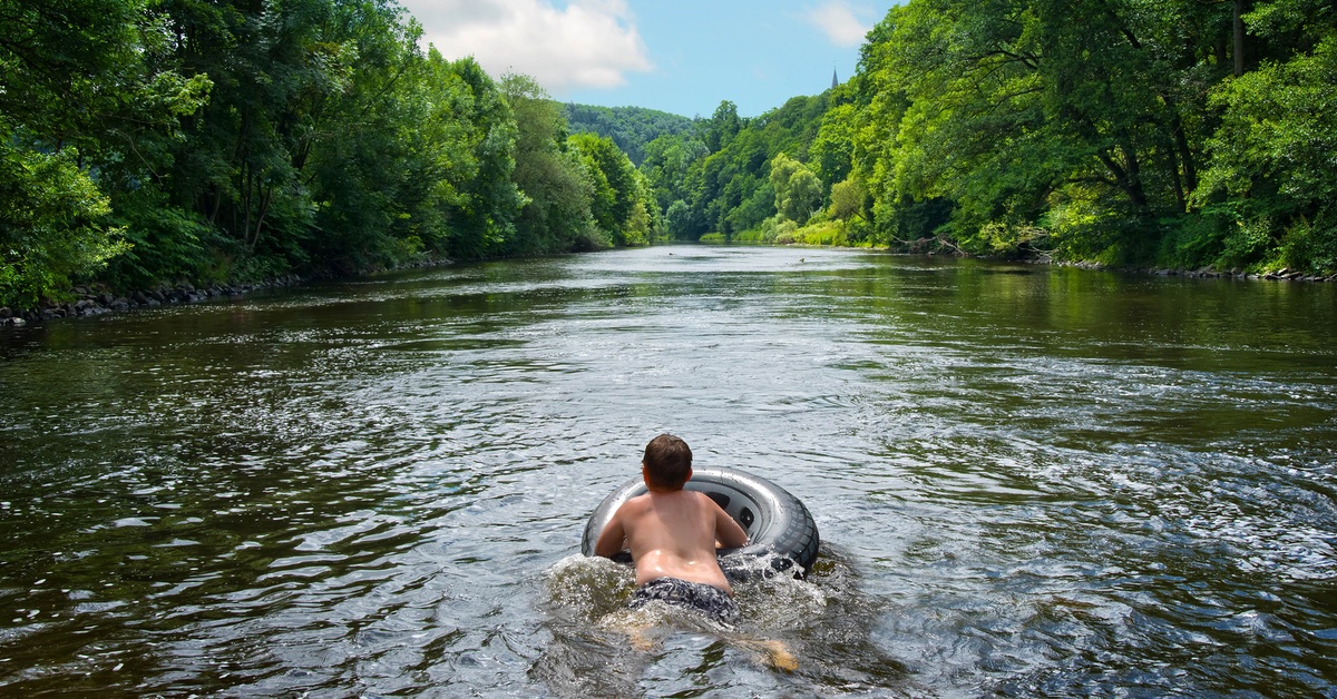 Junge auf einem Reifen in einem Fluss