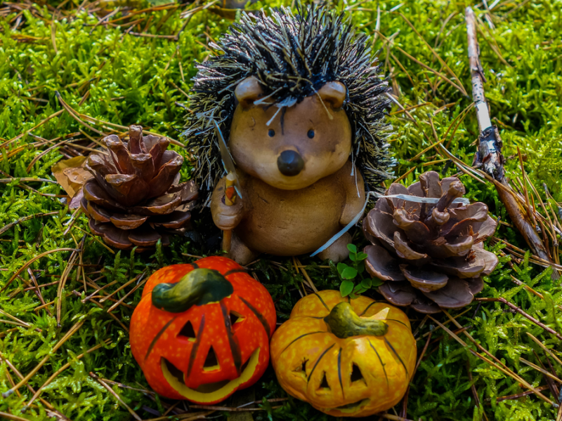 Keramikfiguren wie Kürbisse und Igel auf Gras.