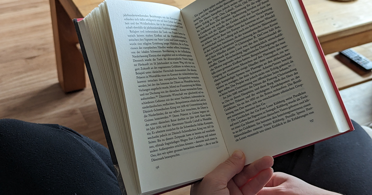 Ein aufgeklapptes Buch wird in Händen gehalten.