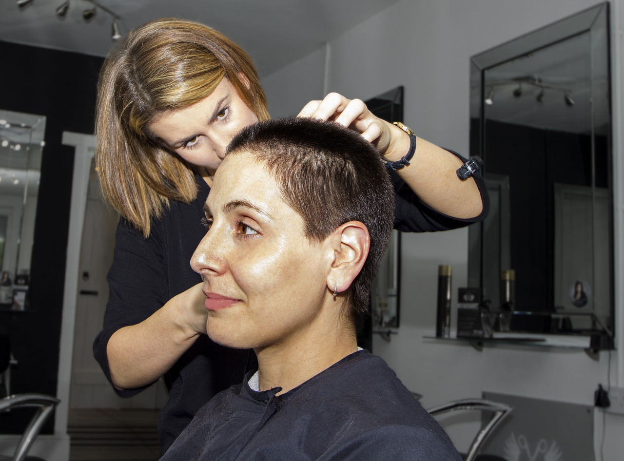 Eine Friseurin schneidet das kurze Haar einer Kundin.