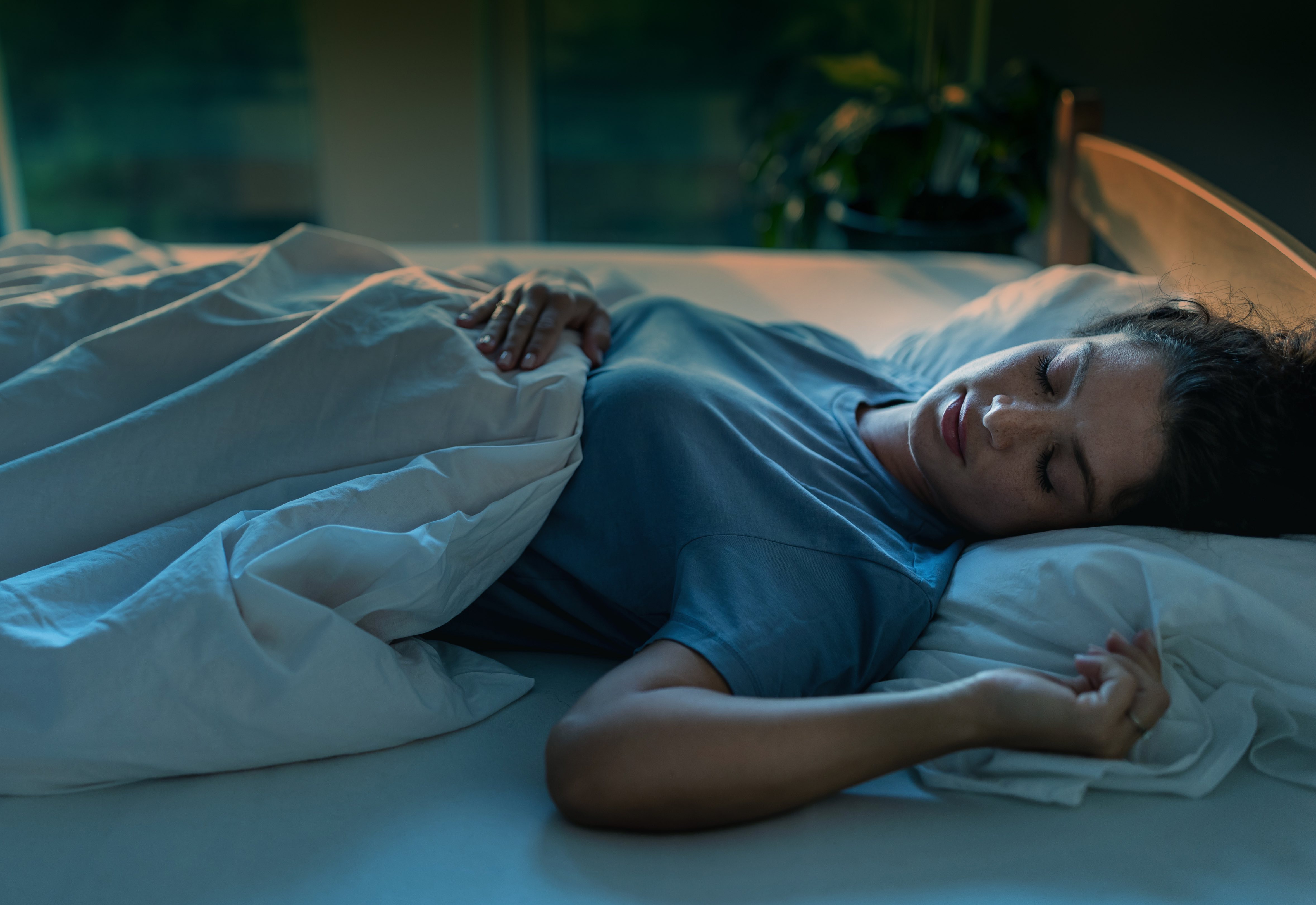 Eine junge Frau schlÃ¤ft in einem Bett. Um bei Hitze besser schlafen zu kÃ¶nnen, solltest du diese BettwÃ¤sche verwenden.