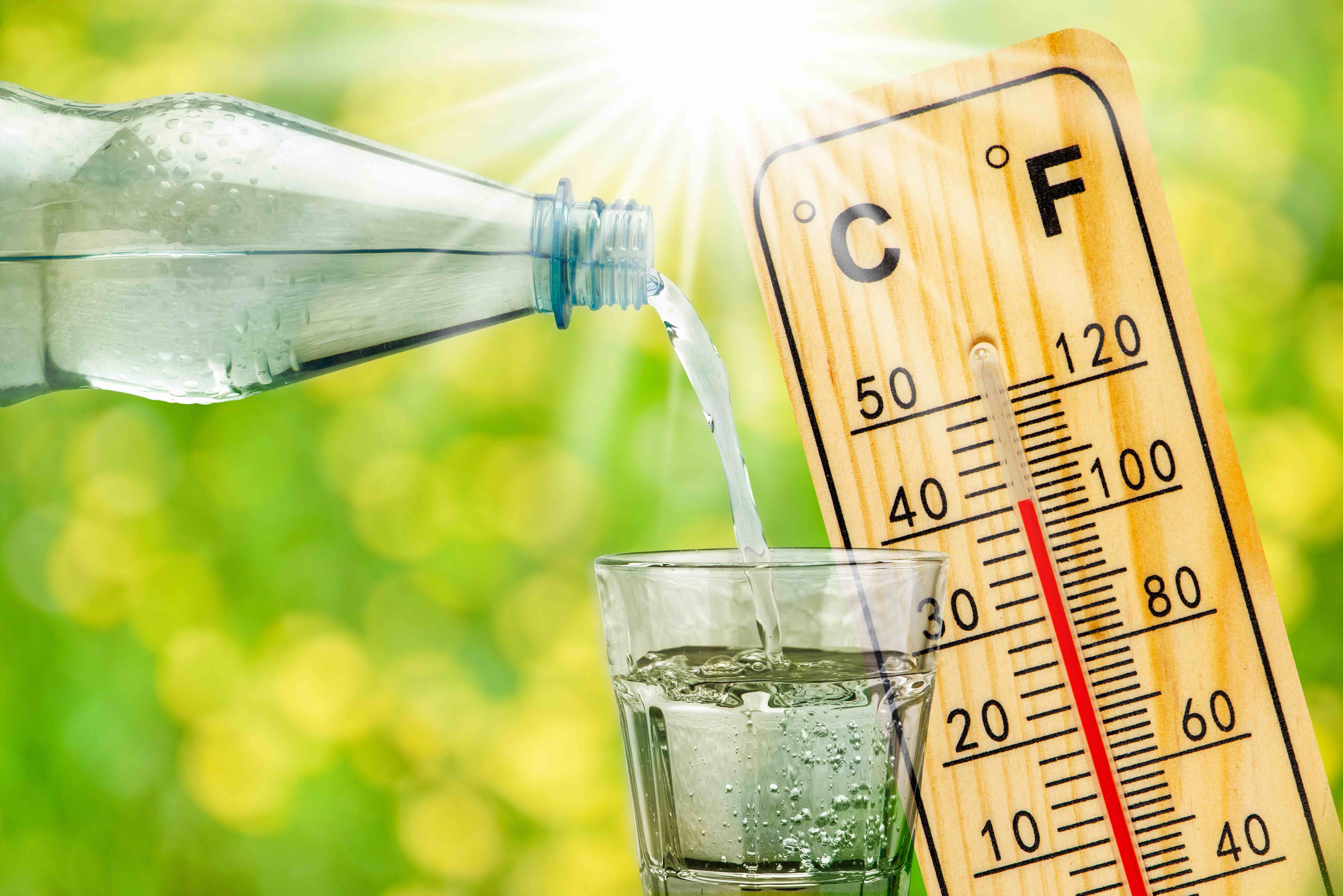 Trinken bei Hitze Ein Glas wird mit Wasser gefüllt. Im Hintergrund ein Thermometer, das 40 °C misst.
