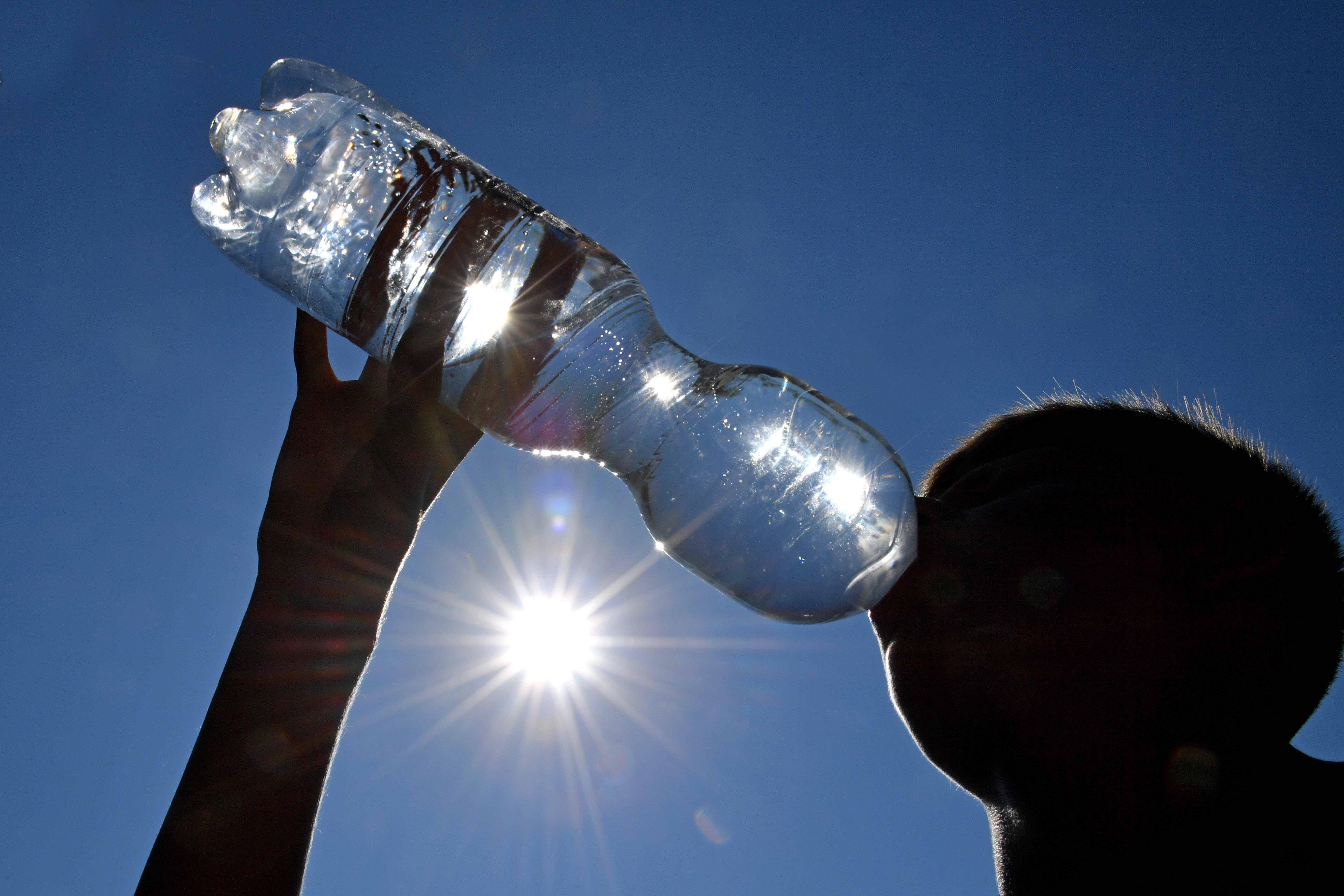 Jemand trinkt bei Hitze Wasser aus einer Plastikflasche.