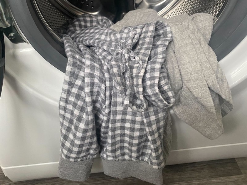 Ein grauer Schlafanzug liegt in der Waschmaschine.