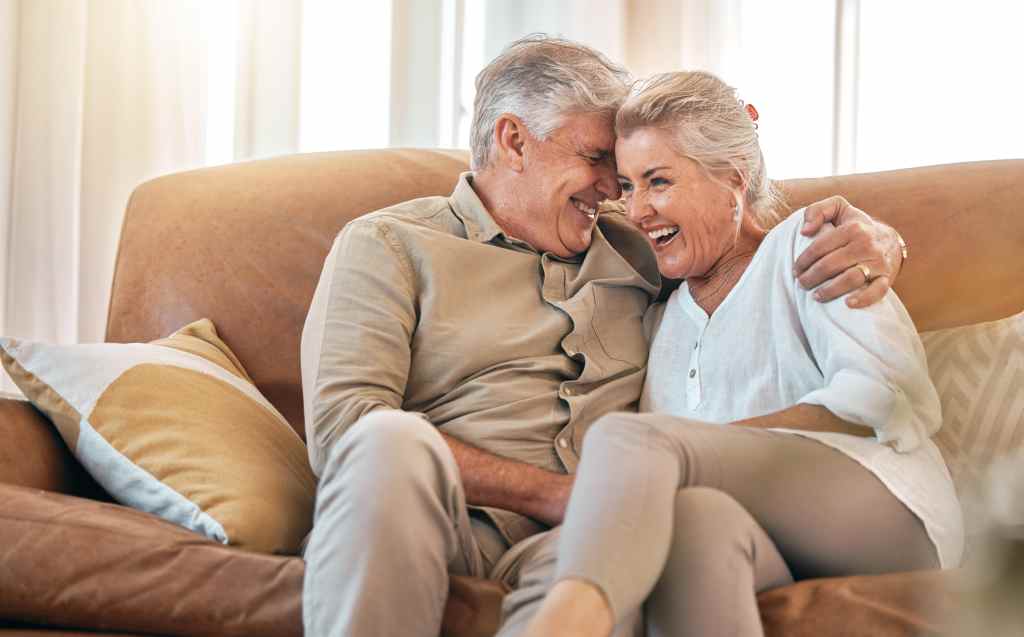 Älteres Paar lacht auf dem Sofa.