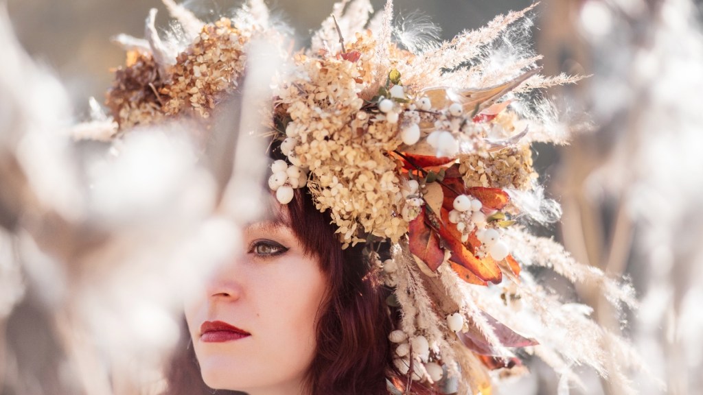 Ein Porträt einer jungen Frau auf einer Hochzeit mit einem Trockenblumen-Kranz auf dem Kopf.
