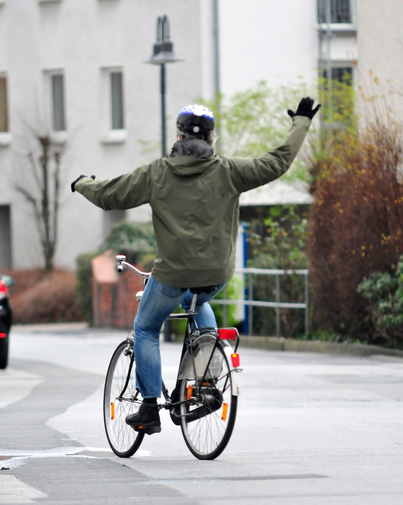 Mann fährt freihändig auf dem Fahrrad.