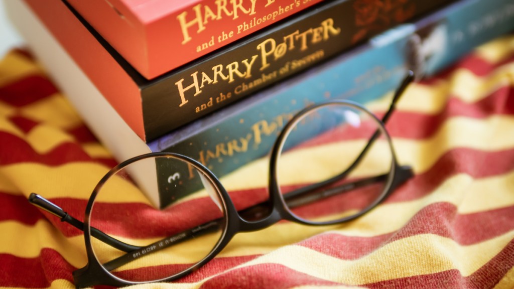 Ein Bücherstapel der Harry-Potter-Bücher mit einer runden Brille davor.