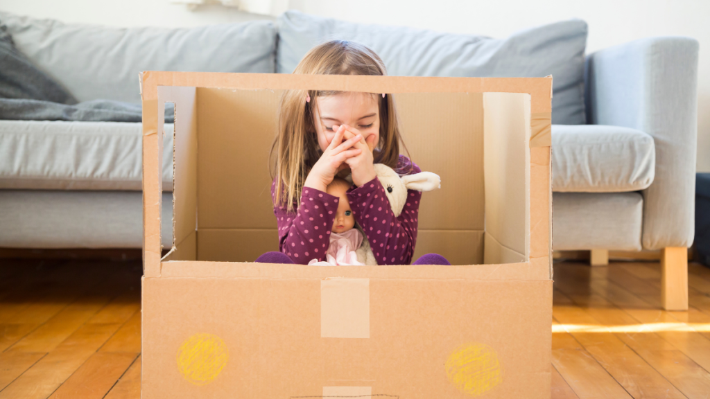 Kind sitzt mit Spielzeug in Kiste