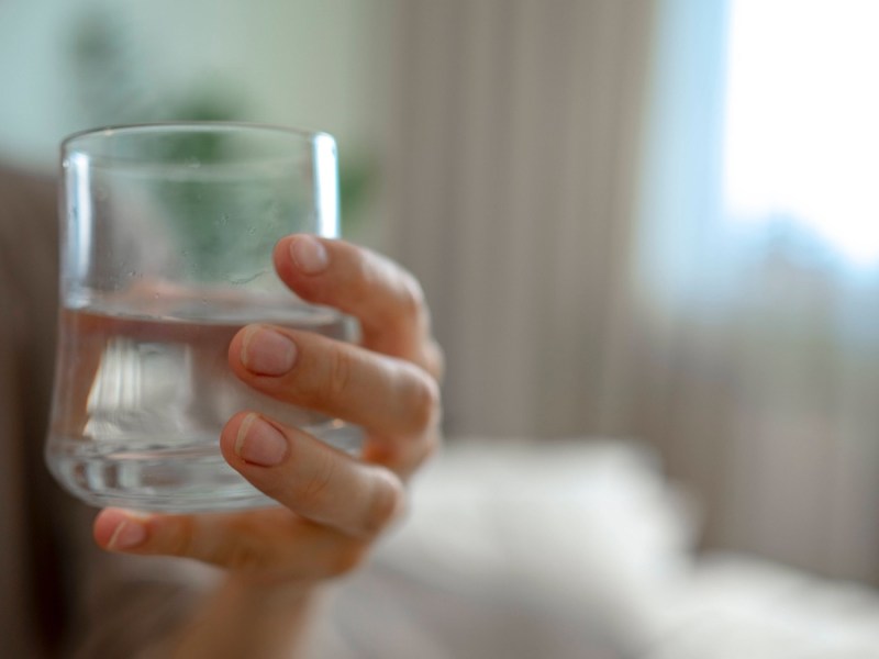 Flüssigkeitsmangel: Eine Frau hält ein Glas Wasser in der Hand.