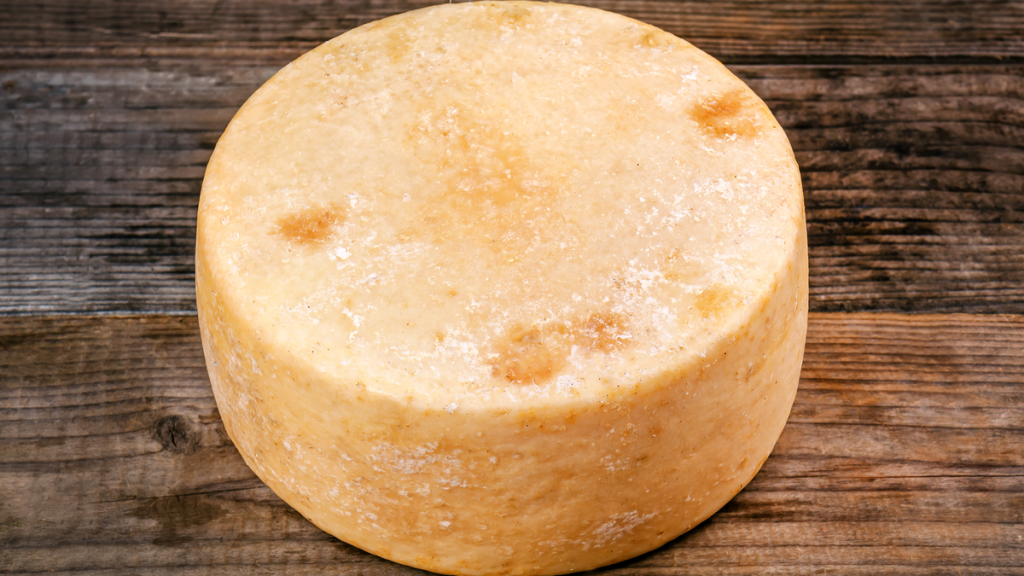 Ein runder Käse liegt auf einem Holztisch.