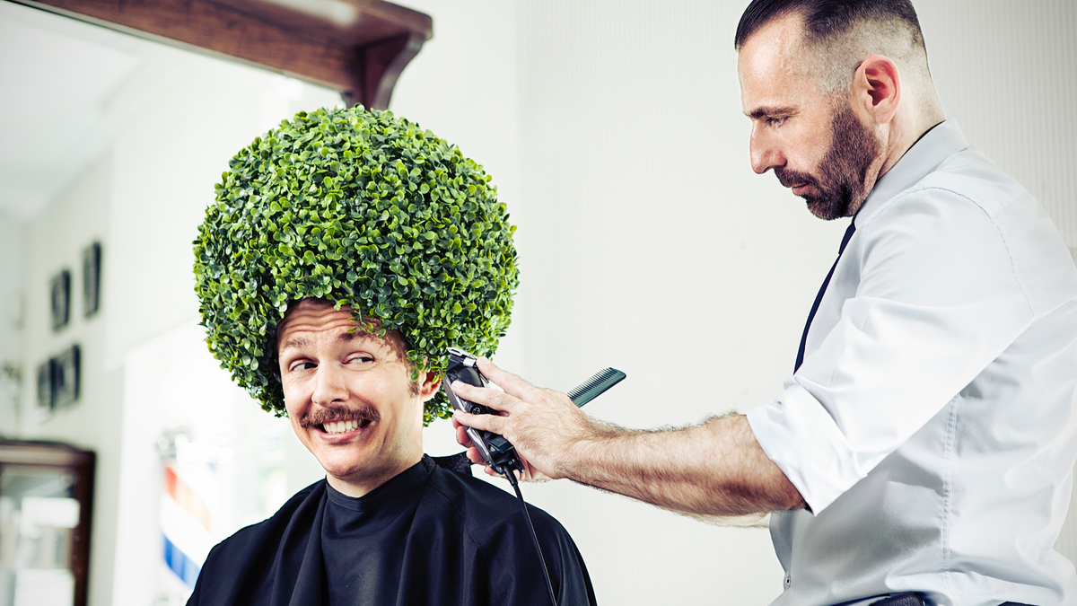 Ein Friseur schneidet die Haare eines Kunden, der Haare wie ein Busch aussehen.