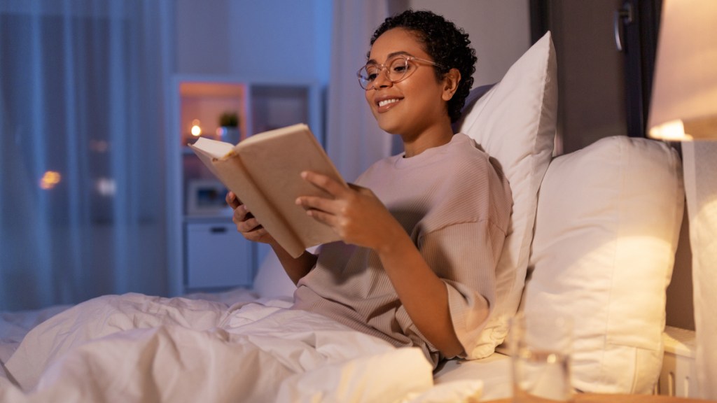 Eine Frau sitzt im Bett und liest ein Buch.