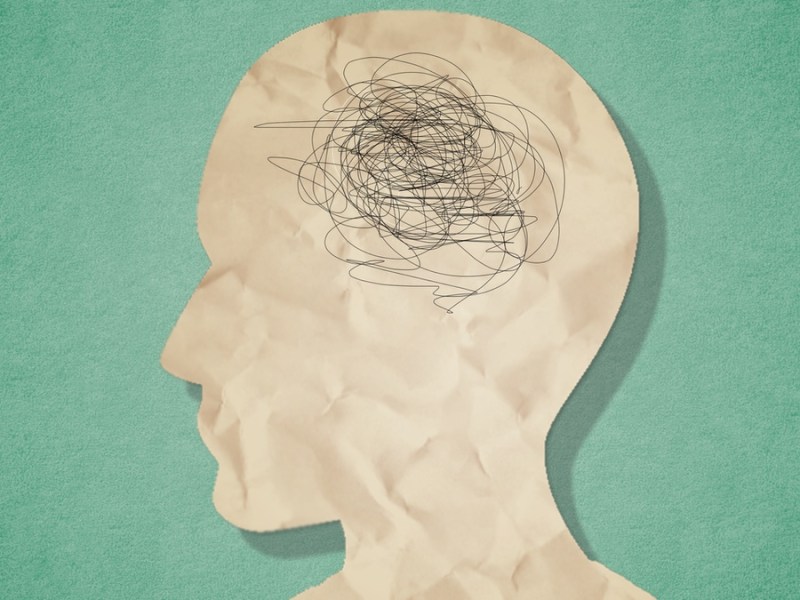 Eine Illustration eines Kopfes mit wirren Gedanken vor einem grünen Hintergrund.