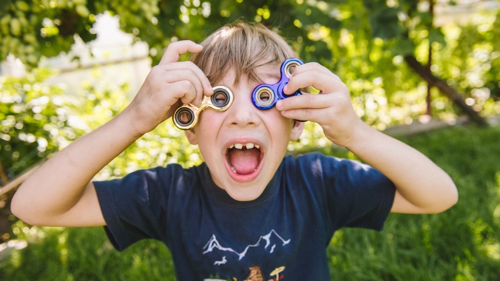 Ein Junge hält sich zwei Fidget Spinner vor die Augen.