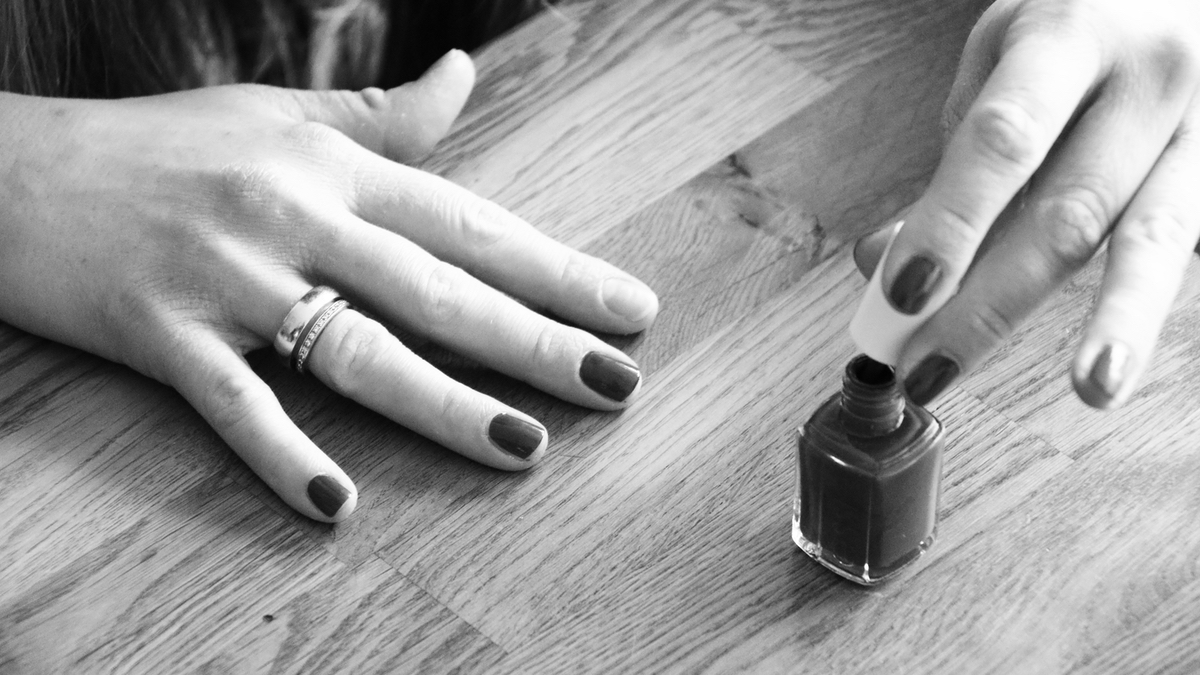 Ein Schwarz-weiß-Bild: Eine Frau lackiert ihre Fingernägel.