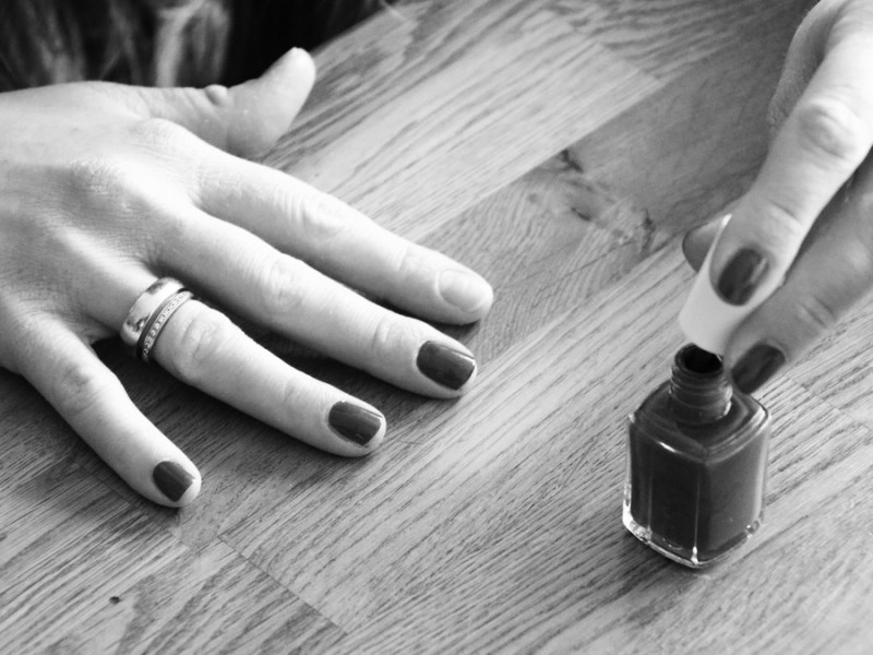 Ein Schwarz-weiß-Bild: Eine Frau lackiert ihre Fingernägel.