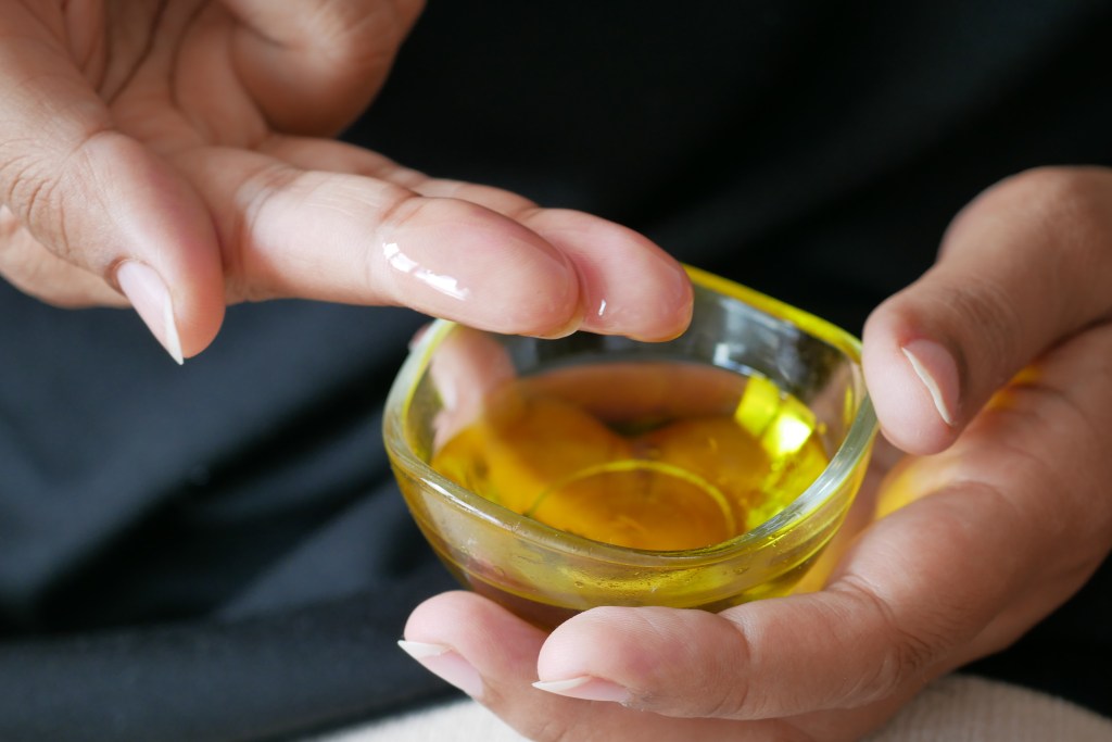 Hand mit Olivenöl.
