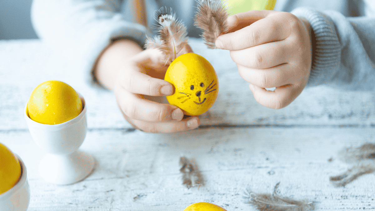 Osterdeko basteln, Kind beklebt gelbes Ei