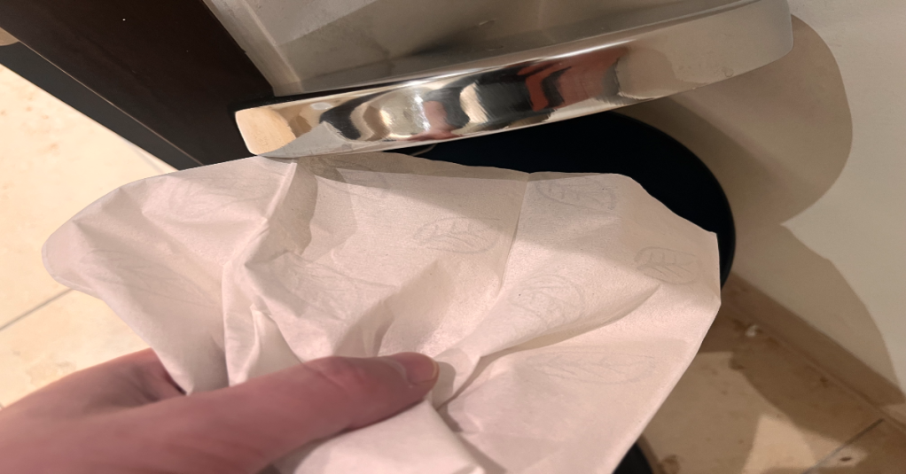 Ein Taschentuch wird in einen Mülleimer geworfen.