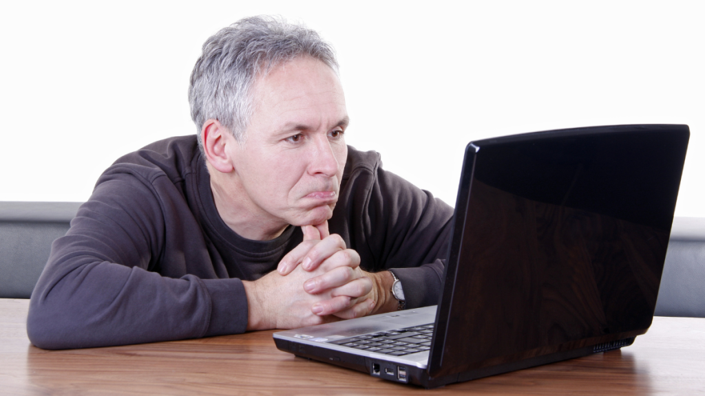 Ein Mann sitzt mit Schmollmund vor seinem Laptop.