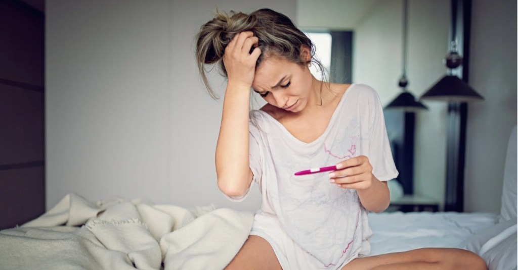 Frau auf Bett Schwangerschaftstest