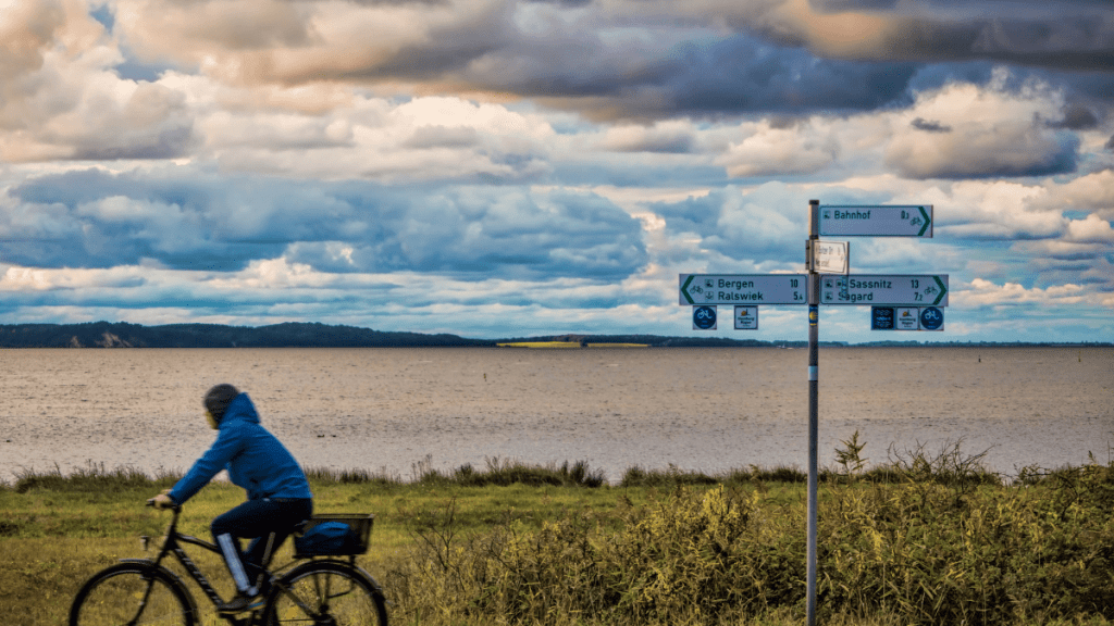 Eine Person fährt Fahrrad. Im Hintergrund ziehen dunkle Wolken auf.