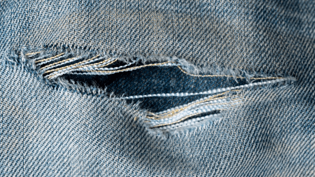 Ein Riss in einer grauen Jeans.