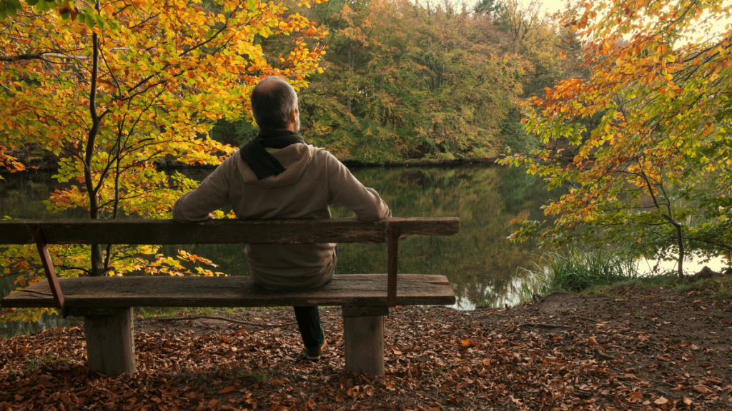 Ein Mann sitzt auf einer Bank im Wald.