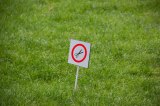 Ein Hinweisschild in einem Rasen, das anzeigt, dass Rasenmähen verboten ist.