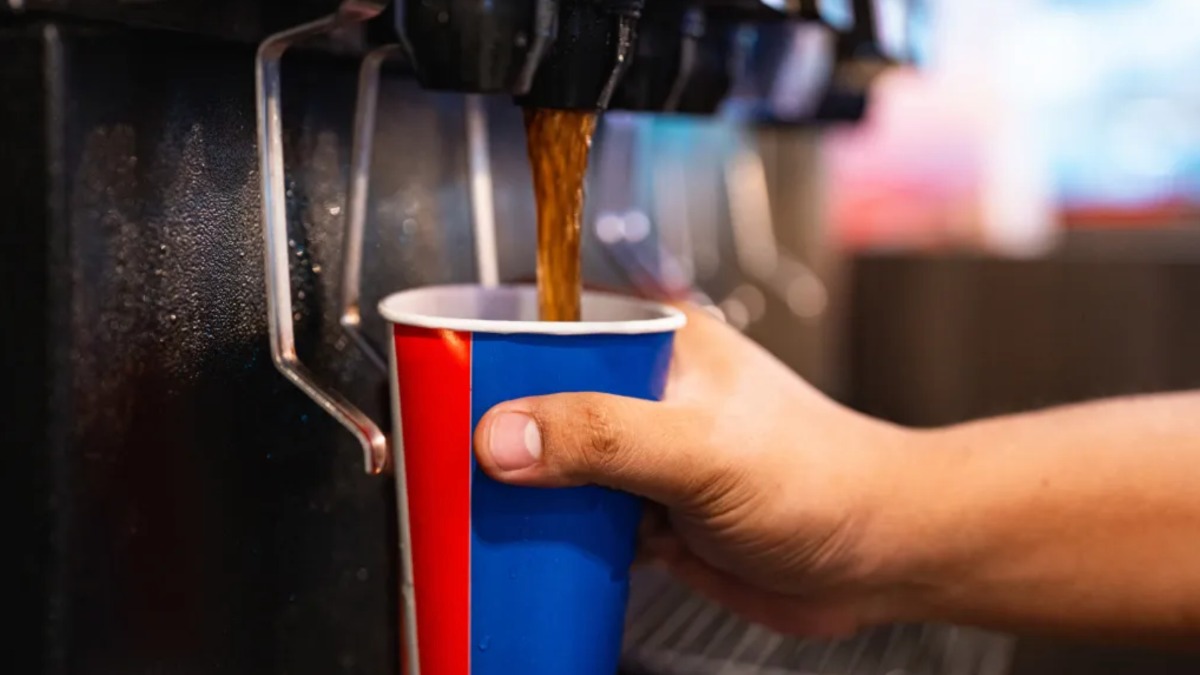 Cola läuft aus einem Automaten in einen Becher