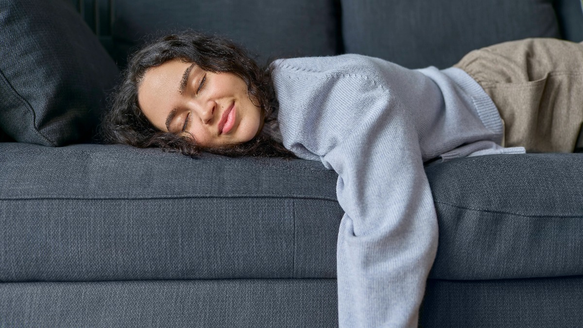 Eine Frau liegt in Bauchlage auf einem Sofa.