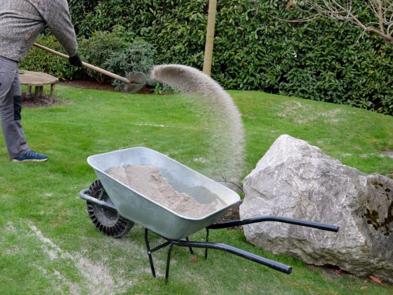 Ein Mann beim Rasen sanden in seinem Garten.