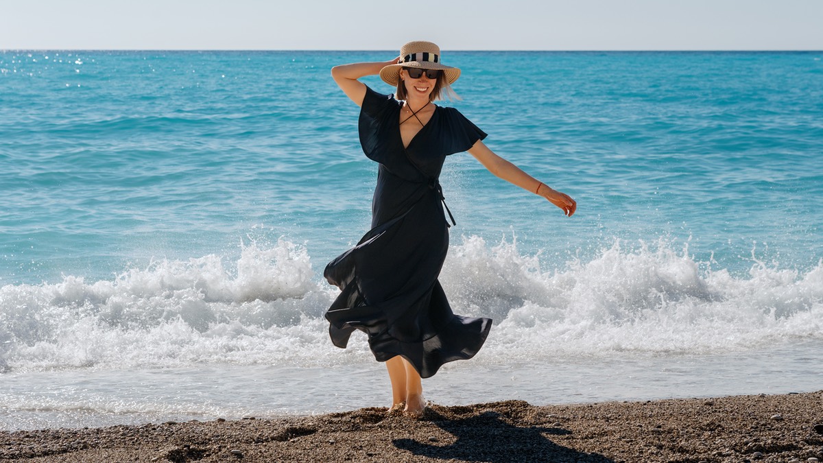 Frau in schwarzem Kleid am Meer.