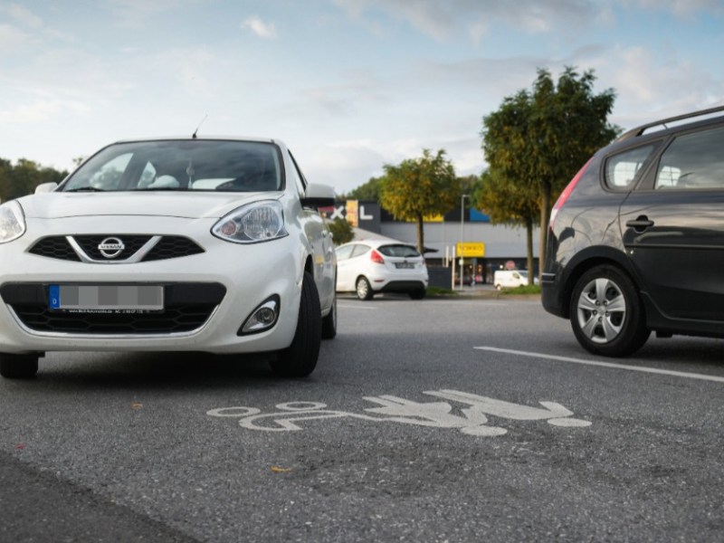 Ein weißes Auto fährst auf einen Mutter-Kind-Parkplatz.