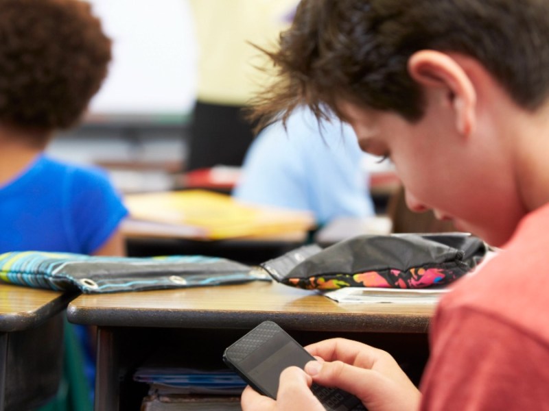 Ein Schüler benutzt ein Handy im Unterricht