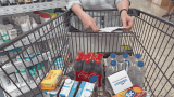 sozialer Status, Frau mit Einkaufszettel stützt sich auf einen gut gefüllten Einkaufswagen.