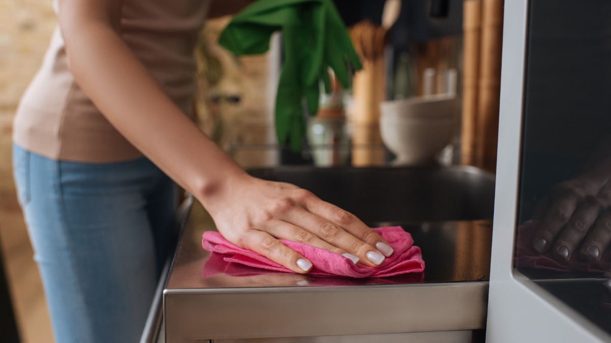 eine Frau wischt eine Küchenarbeitsplatte mit einem Tuch ab