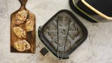 eine geöffnete Heißluftfritteuse und daneben Koteletts auf einem Holzbrett
