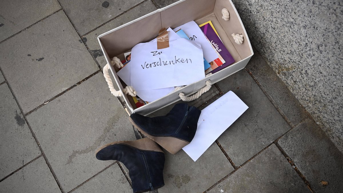 Eine „Zu verschenken“-Kiste am Straßenrand mit Büchern und Schuhen.