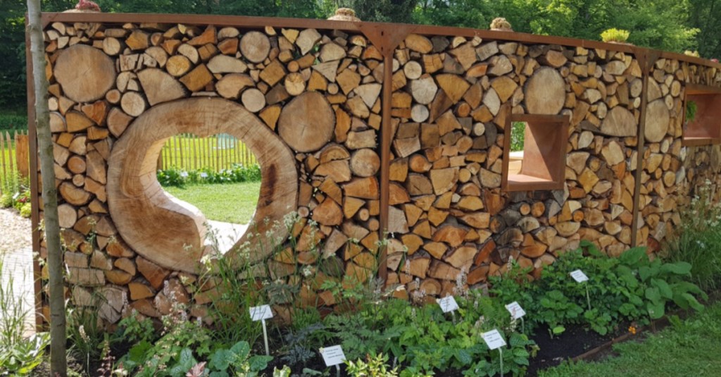ein Sichtschutz im Garten aus Holzscheiten