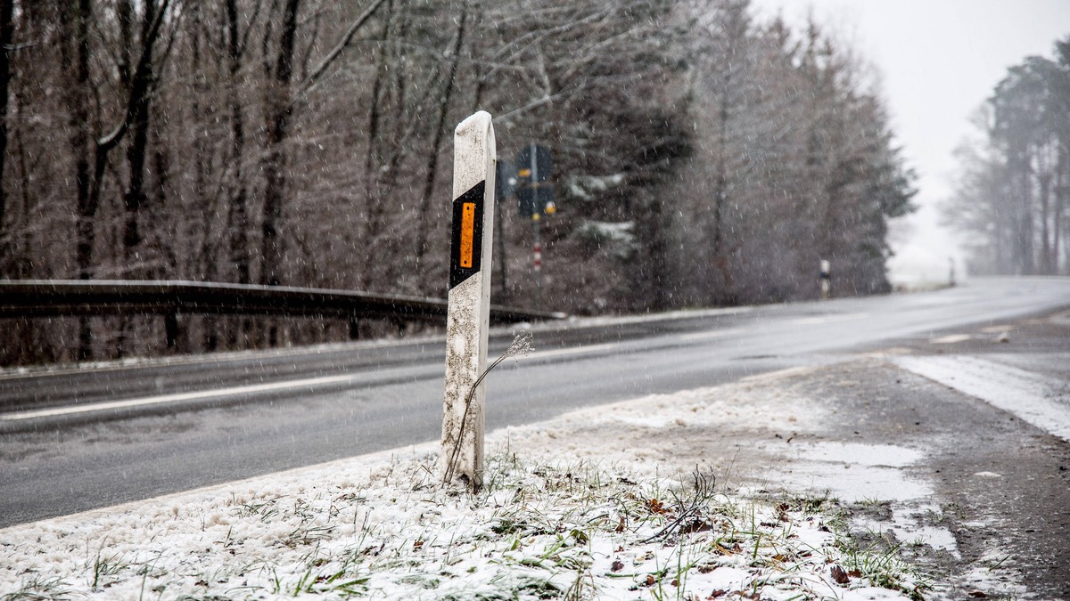 Leitpfosten am rechten Straßenrand im Winter.