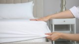 eine Frau zieht ein Spannbettlaken auf ein Bett