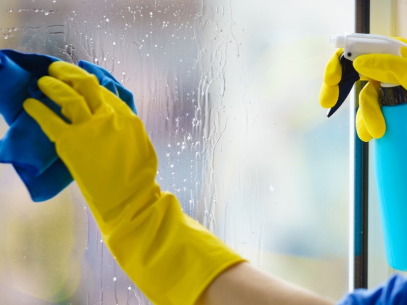 Mieter Fenster putzen: jemand putzt mit gelben Handschuhen ein Fenster