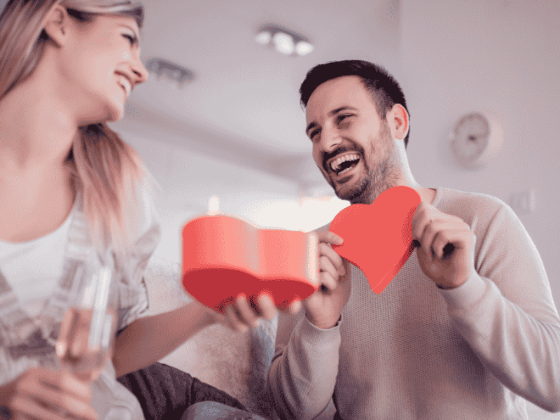 Valentinstags-Date-Box-Ideen, Paar packt Geschenk in Herzform aus.