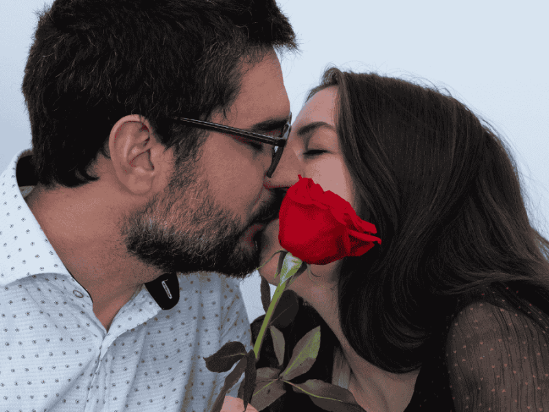 Valentinstag-Ideen, küssendes Paar mit roter Rose