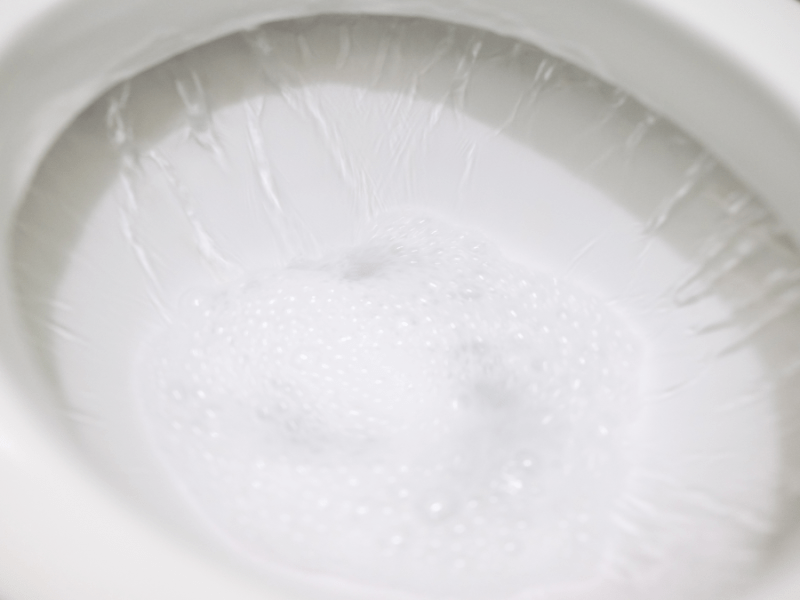 Eine Toilette wird mit WC-Reiniger gespült und Schaum entsteht.