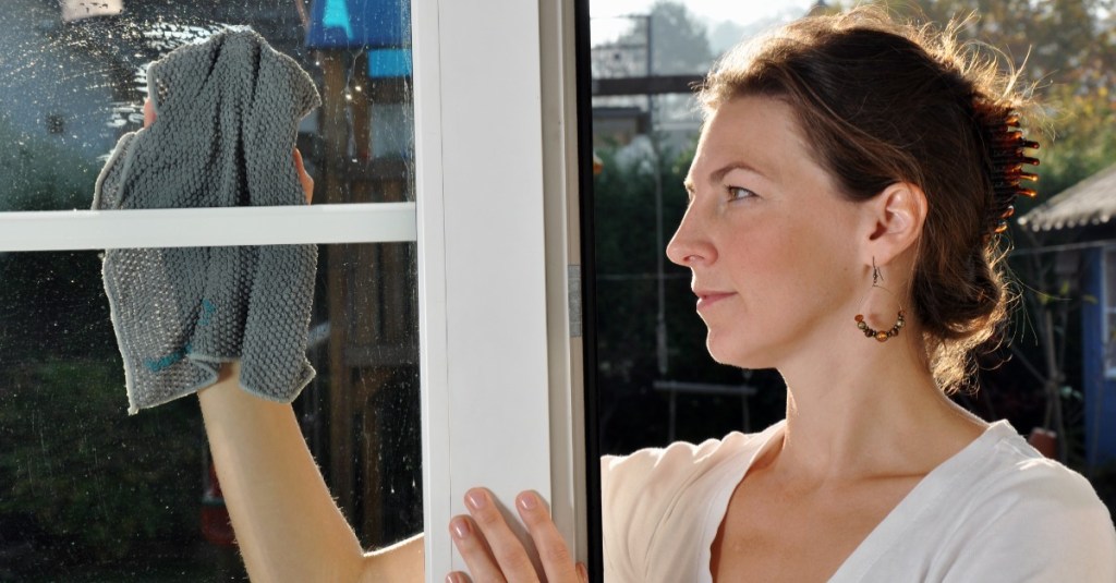Fenster reinigen: eine Frau putzt ihr Fenster mit einem Tuch