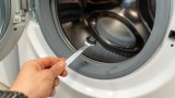 Jemand repariert seine Waschmaschine, weil sie das Wasser nicht mehr abpumpt.